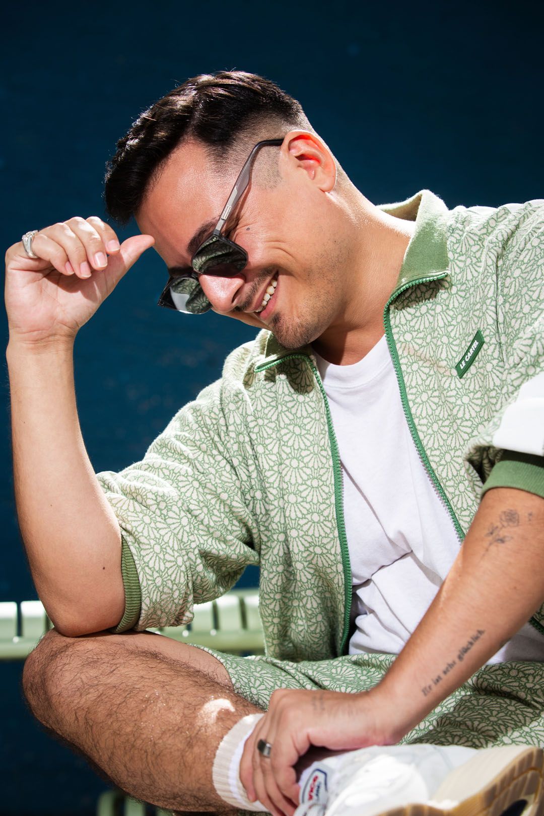 Jonas lacht, eine Hand an der Sonnenbrille